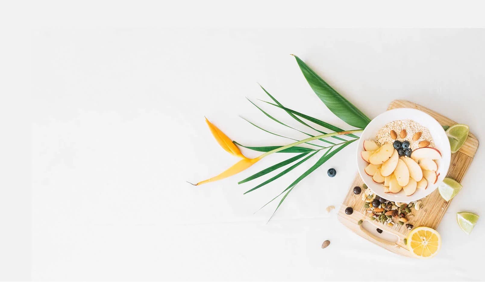 An oat bowl topped with sliced apple, blueberries and almonds, plated on a wooden board