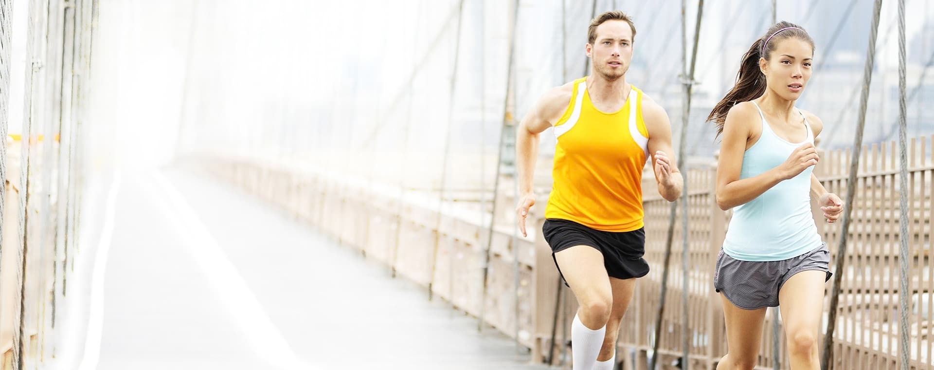 A man and woman running together on a pedestrian bridge